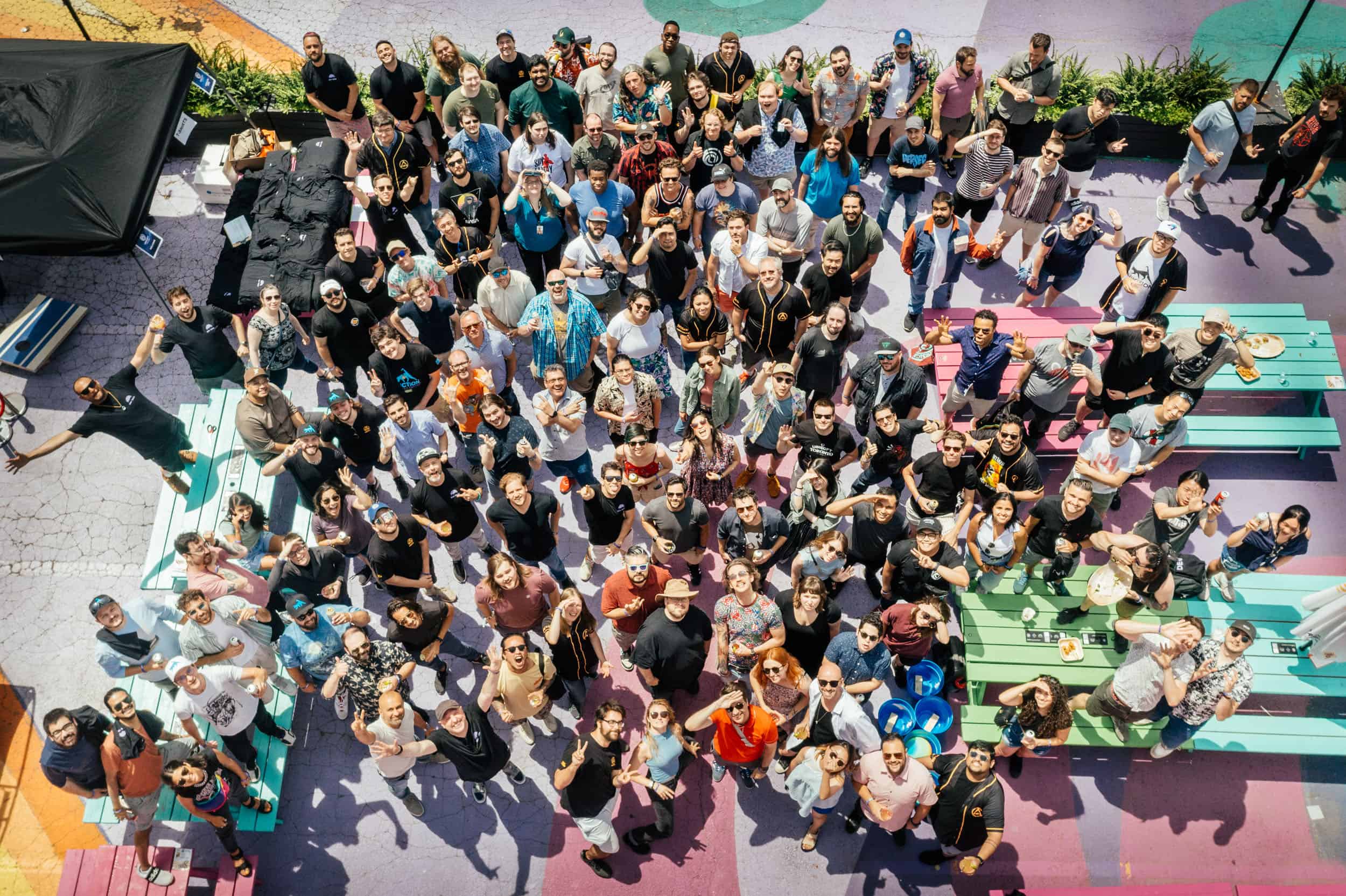 Top-down photo of a crowd of Ubisoft employees outside in downtown Toronto standing on a pastel-painted ground and picnic benches